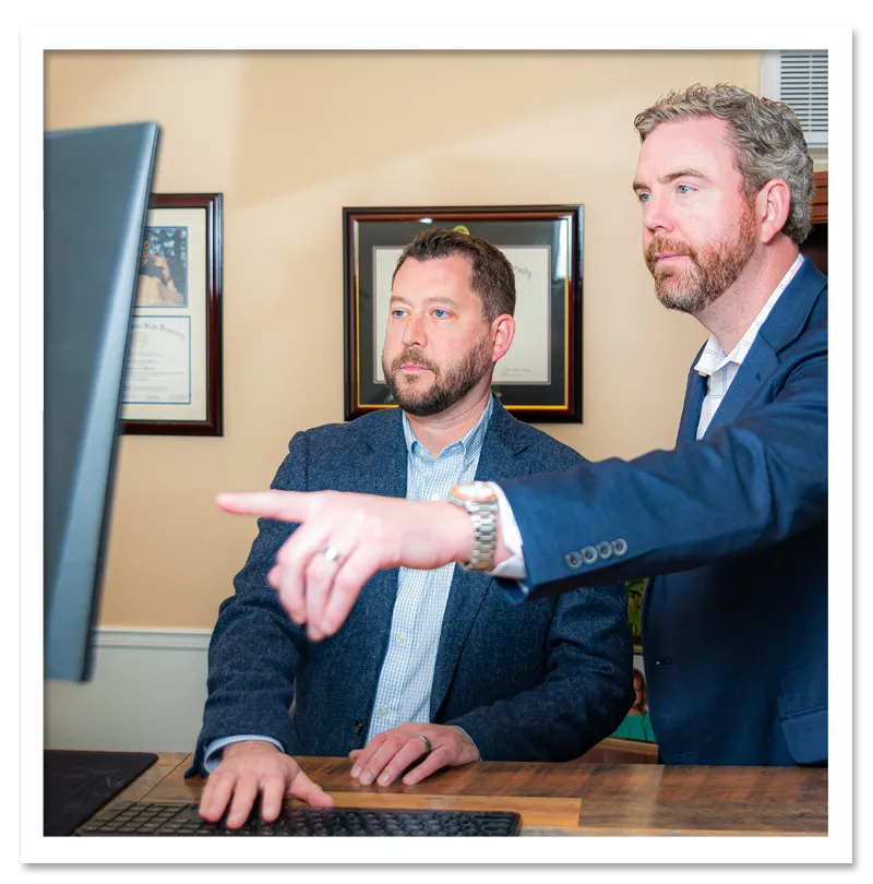 Ethan and Daniel sitting at a computer working together on discussing a case.