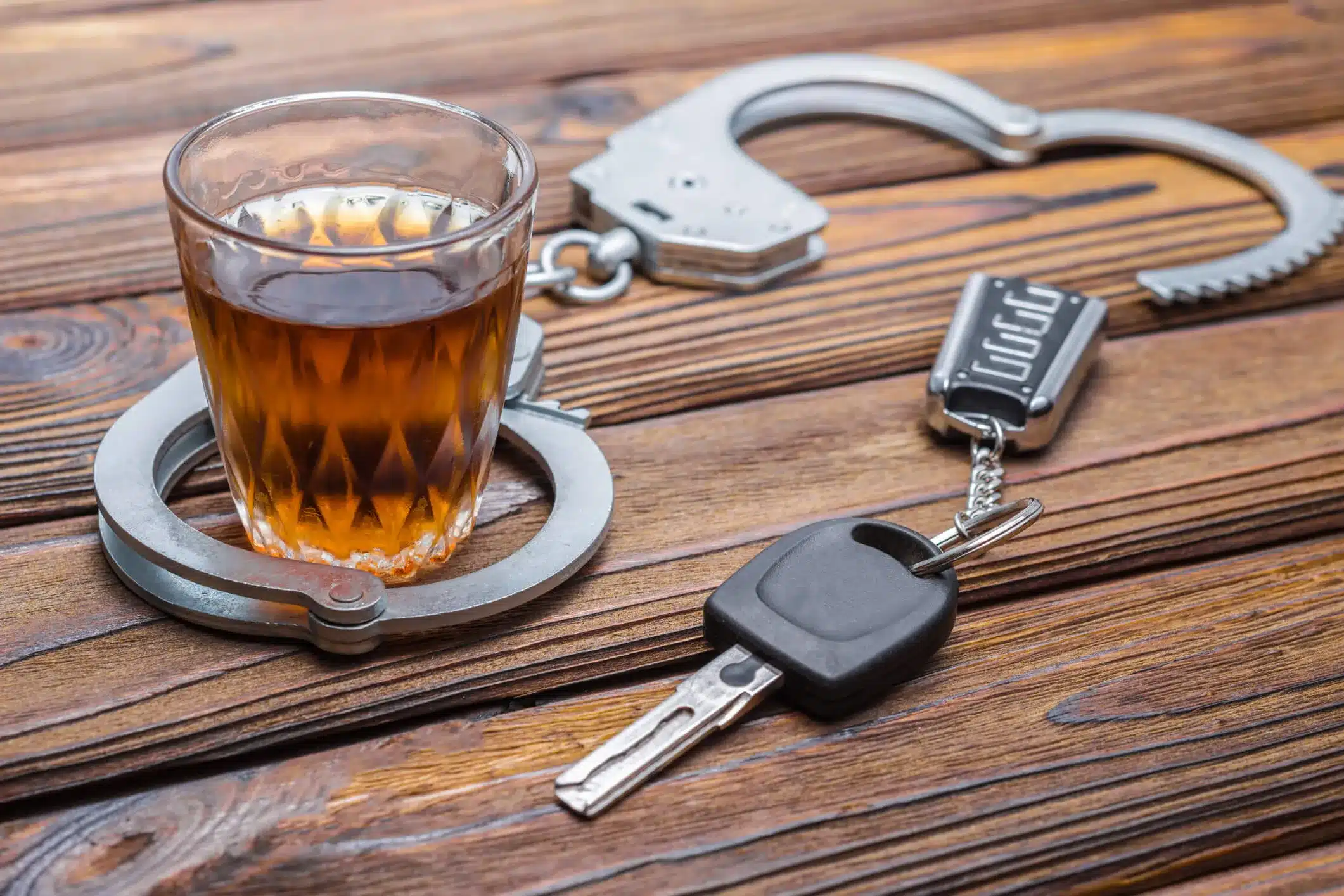 A beer next to handcuffs and keys.