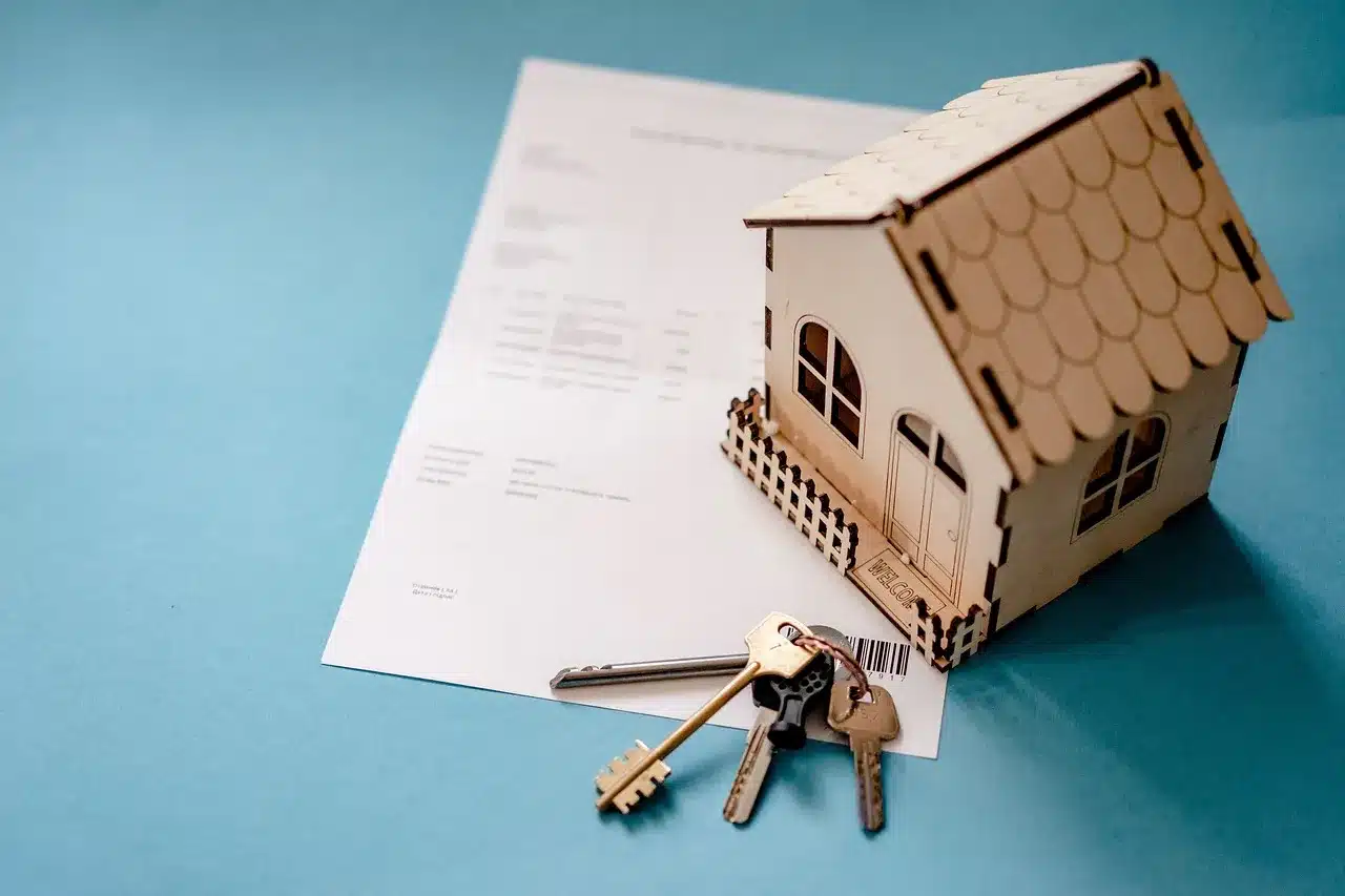 Paperwork, a model home and keys on a table.