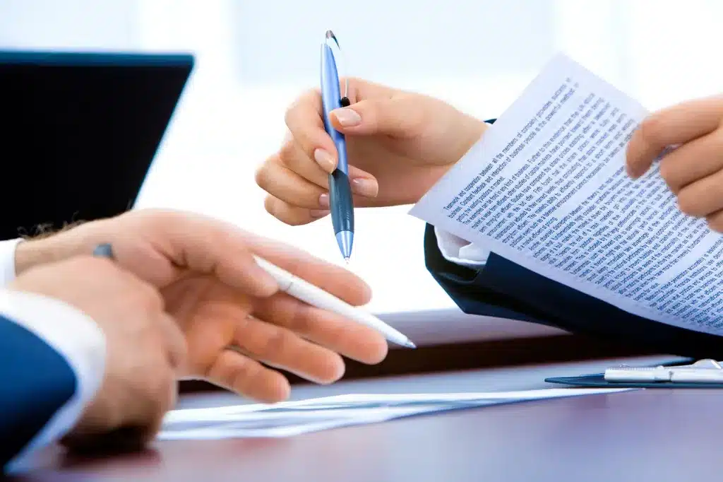 Two people reviewing and signing paperwork.