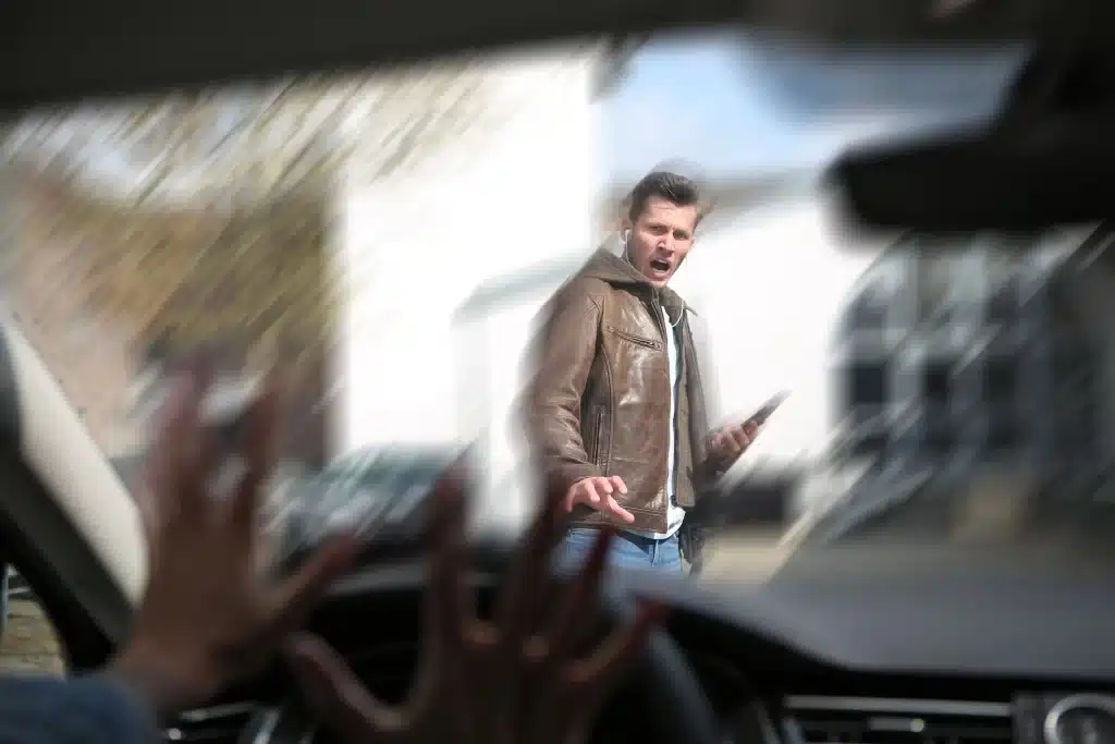 Pedestrian crossing the street, in danger of getting hit by car.
