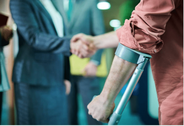 Injured man with crutches shakes hands with a lawyer.