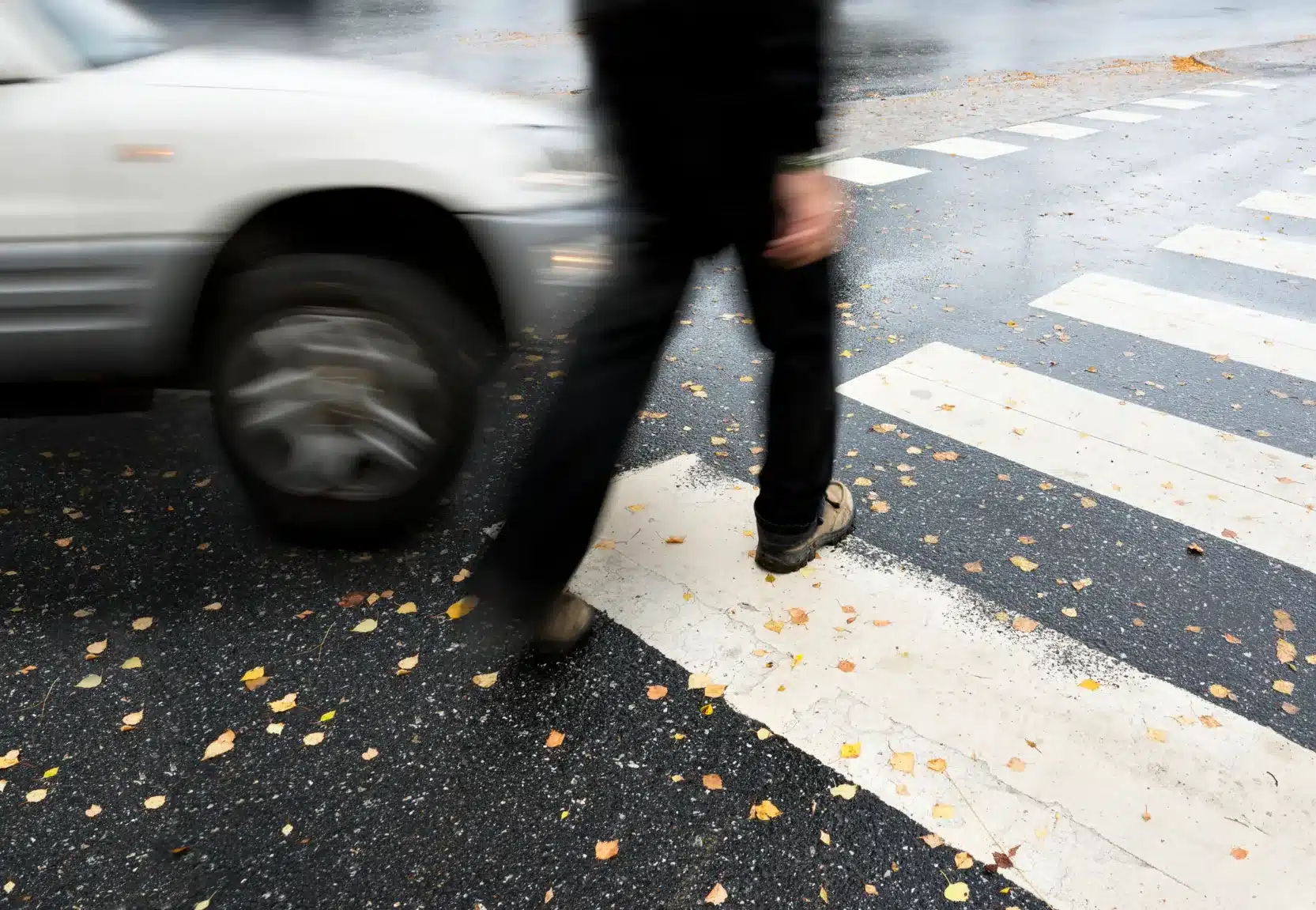 A pedestrian crossing the street with a car about to hit them.