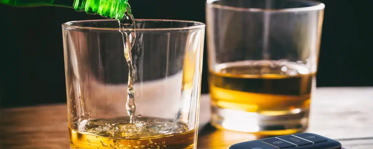 Pouring beer into a glass next to car keys.
