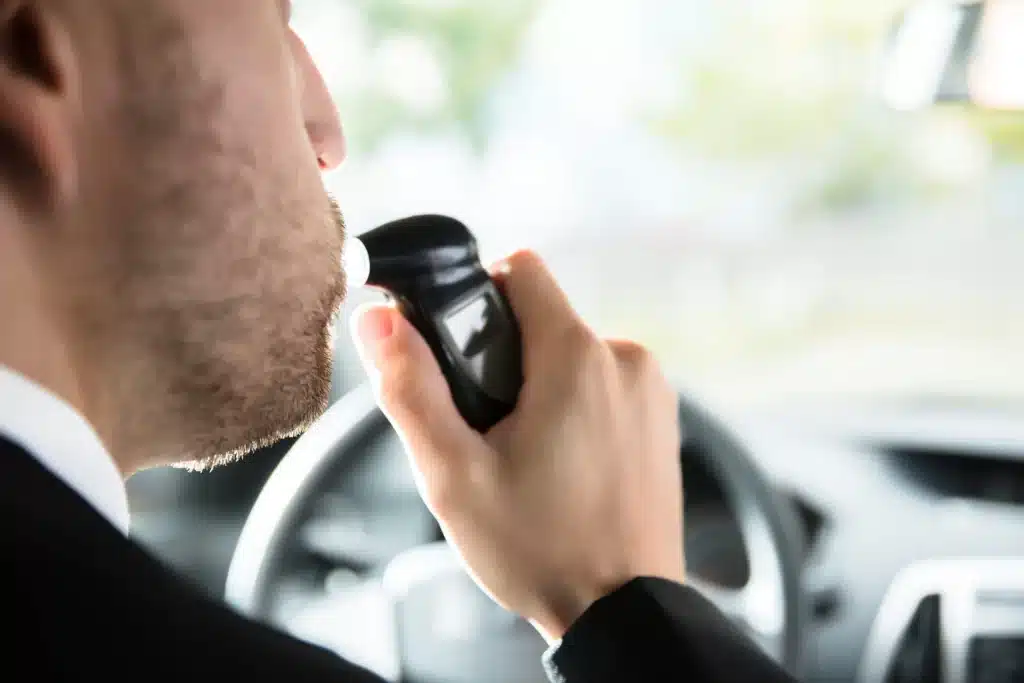 A man blowing into his ignition interlock device.