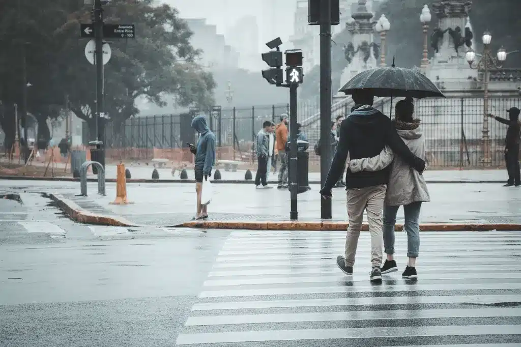 A couple of pedestrians walking across a crosswalk.