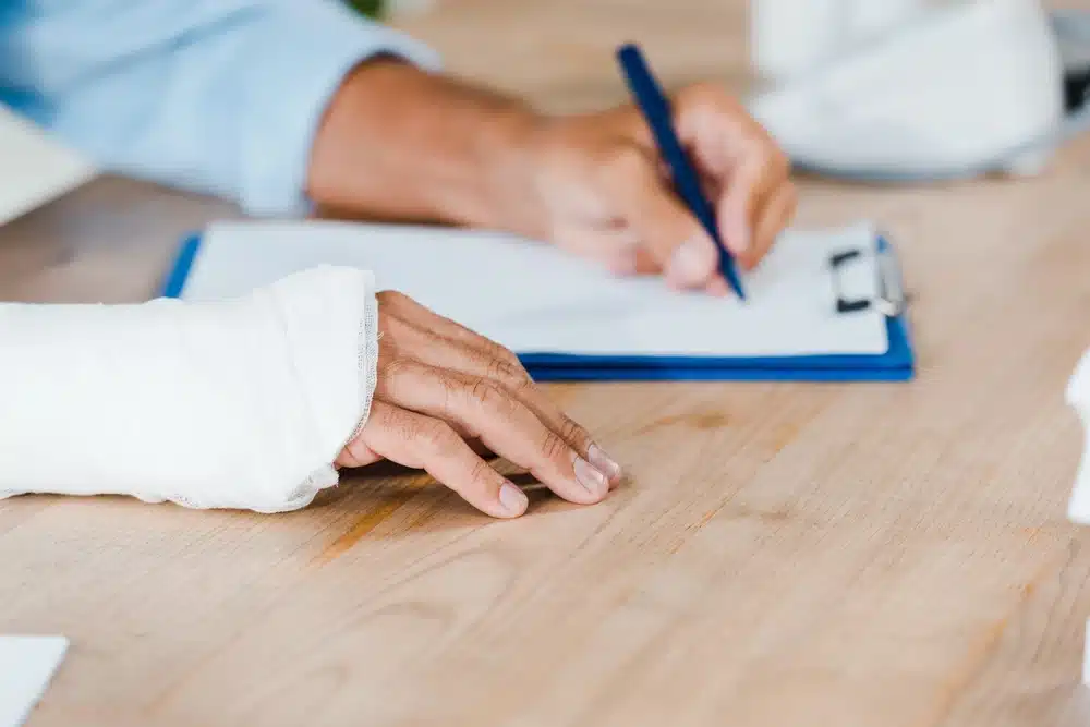 personal injury client signing legal paperwork with a broken arm in cast